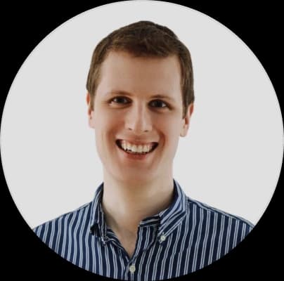 Keegan Robbins -smiling person with short hair wearing a blue and white striped shirt, set against a plain white background.